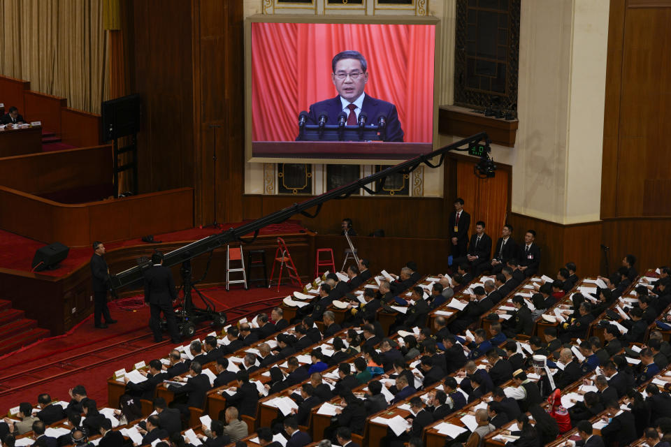 Chinese Premier Li Qiang, on screen, speaks during the opening session of the National People's Congress (NPC) at the Great Hall of the People in Beijing, China, Tuesday, March 5, 2024. (AP Photo/Ng Han Guan)