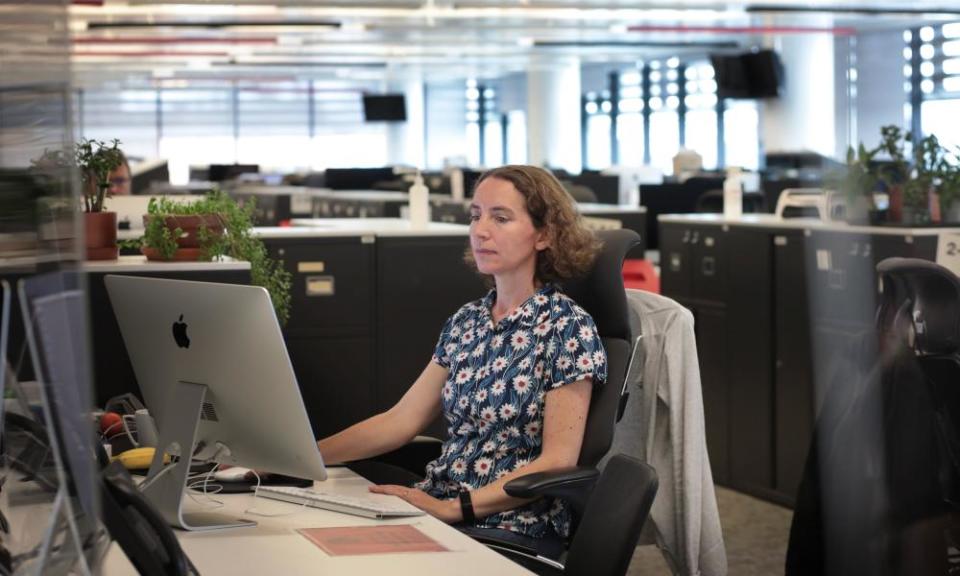 Suzanne Warr at her desk, looking at a Mac