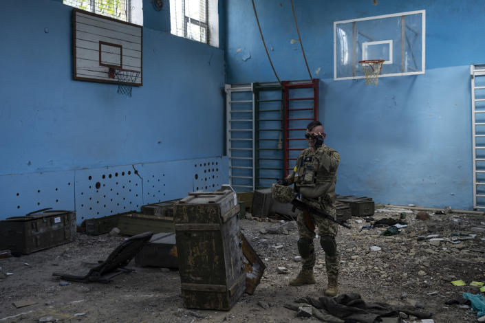 A Ukrainian serviceman inspects a school damaged during a battle between Russian and Ukrainian forces in the village of Vilkhivka, on the outskirts of Kharkiv, in eastern Ukraine, Friday, May 20, 2022. (AP Photo/Bernat Armangue)