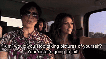 A GIF of Kim Kardashian taking a selfie while her sister goes to jail