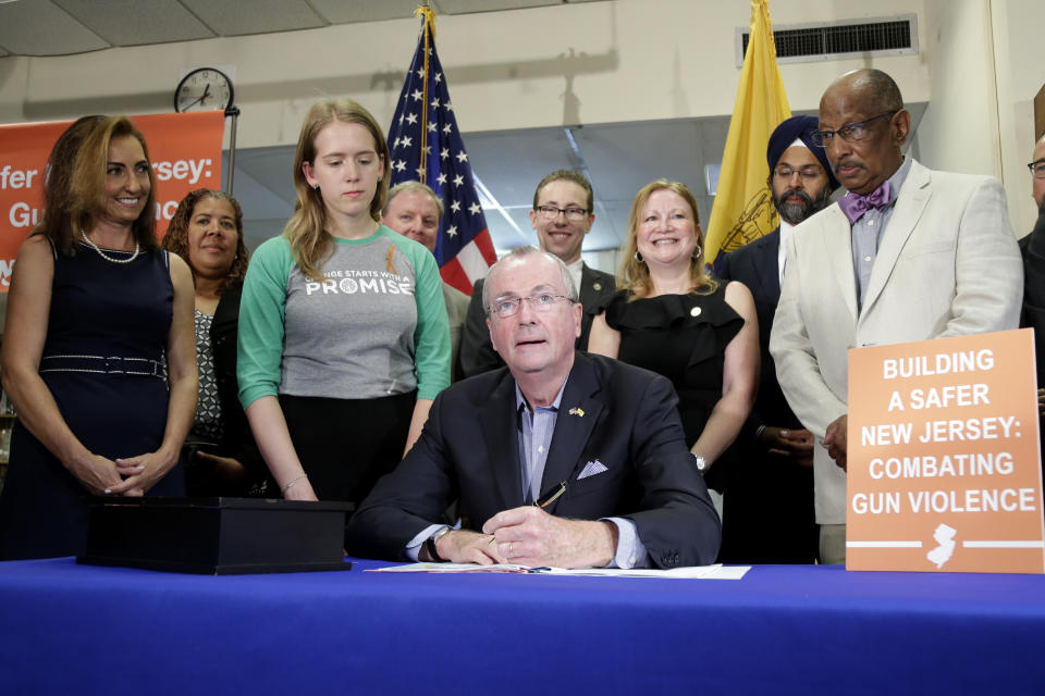 New Jersey Gov. Phil Murphy, center, signs a gun control bill during a ceremony in Berkeley Heights, N.J., Tuesday, July 16, 2019. Murphy has signed a measure aimed at making so-called smart guns available in the state. He also signed three other measures aimed at reining in gun violence. (AP Photo/Seth Wenig)