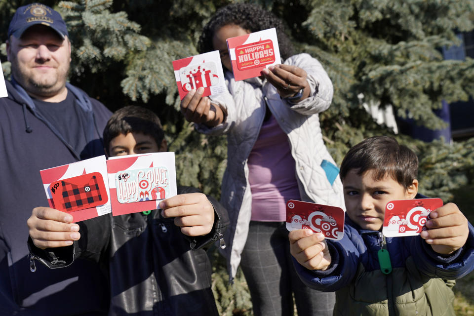 Sornic, left, and Gabriel hold gift cards received by their parents, Aaron and Sheyla Crawford, outside their Apple Valley, Minn., home on Saturday, Nov. 21, 2020. The couple turned to a Minnesota nonprofit, 360 Communities, part of Feeding America's food bank network, when the pandemic's economic fallout put them in peril. The couple and their two young sons are among the millions who've flocked to food banks as hunger has reached record levels since the virus took hold in America. The Crawfords are now getting aid from federal food stamps. (AP Photo/Jim Mone)