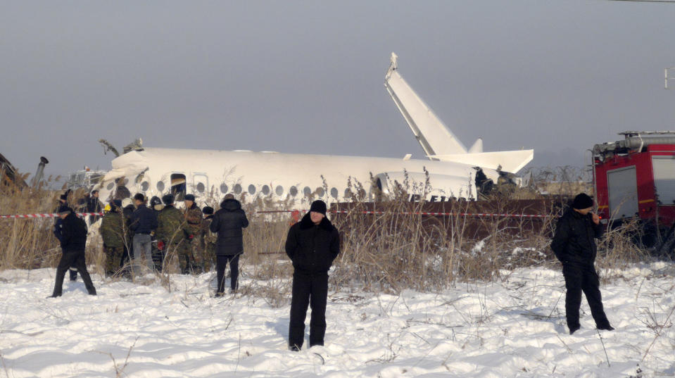 Police stand guard as rescuers assist on the site of a plane crash near Almaty International Airport, outside Almaty, Kazakhstan, Friday, Dec. 27, 2019. Almaty International Airport said the Bek Air plane crashed Friday in Kazakhstan shortly after takeoff causing numerous deaths. The aircraft had 100 passengers and crew onboard when hit a concrete fence and a two-story building shortly after takeoff. (AP Photo/Vladimir Tretyakov)