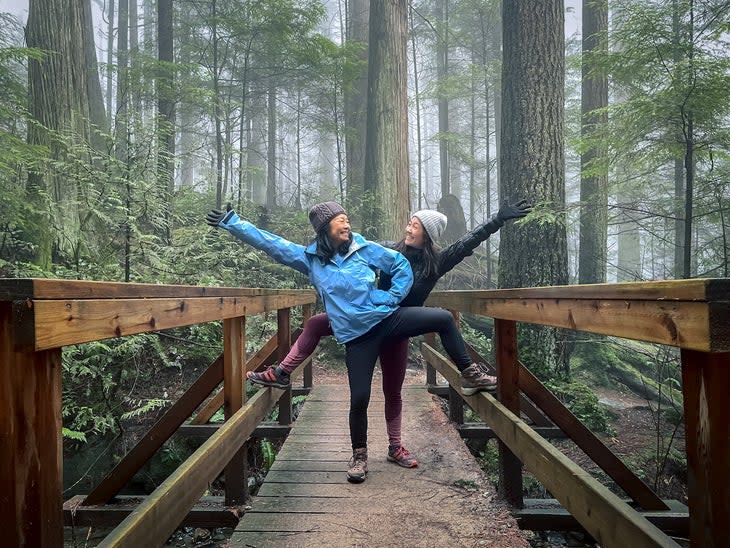 two women standing on bridge while hiking in woods