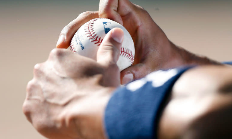 A baseball player holding a baseball with the MLB's logo on it.