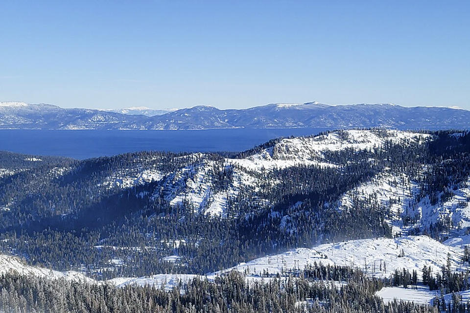 ADDS NAME OF SKI RESORT - Lake Tahoe is seen behind a snow covered mountain near Palisades Tahoe, California ski resort, on Thursday, Jan. 11, 2024, in Calif. After closing down every lift and trail in the avalanche's aftermath, Palisades Tahoe reopened many runs on Thursday. But its iconic KT-22 lift, which serves the area of mostly expert runs where the slide occurred, remained closed while crews worked to clear a road to enable snowcats and snowmobiles to enter and clean up. (Mark Sponsler via AP)