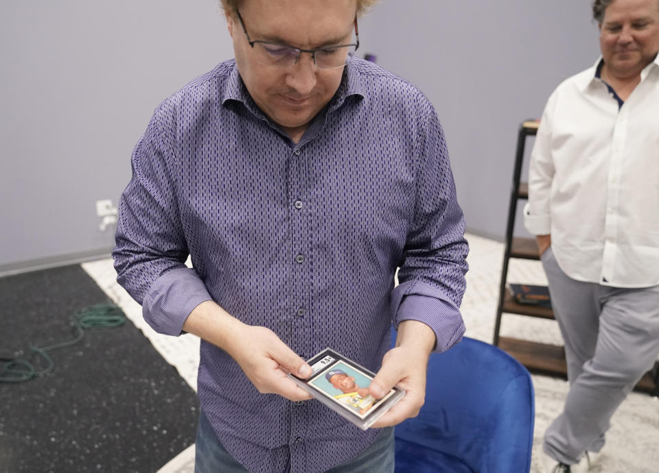 Derek Grady, left, handles a rare Mickey Mantle baseball card as Chris Ivy looks on at Heritage Auctions in Dallas, Thursday, July 21, 2022. The mint-condition Mantle card is expected to sell well into the millions when bidding ends at the end of the month. (AP Photo/LM Otero)