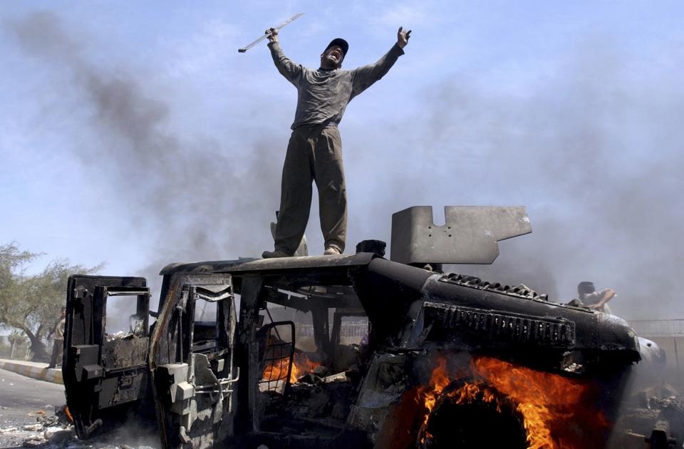 FILE - An Iraqi man celebrates atop of a burning U.S. Army Humvee in the northern part of Baghdad, Iraq, April 26, 2004. (AP Photo/Muhammed Muheisen, File)