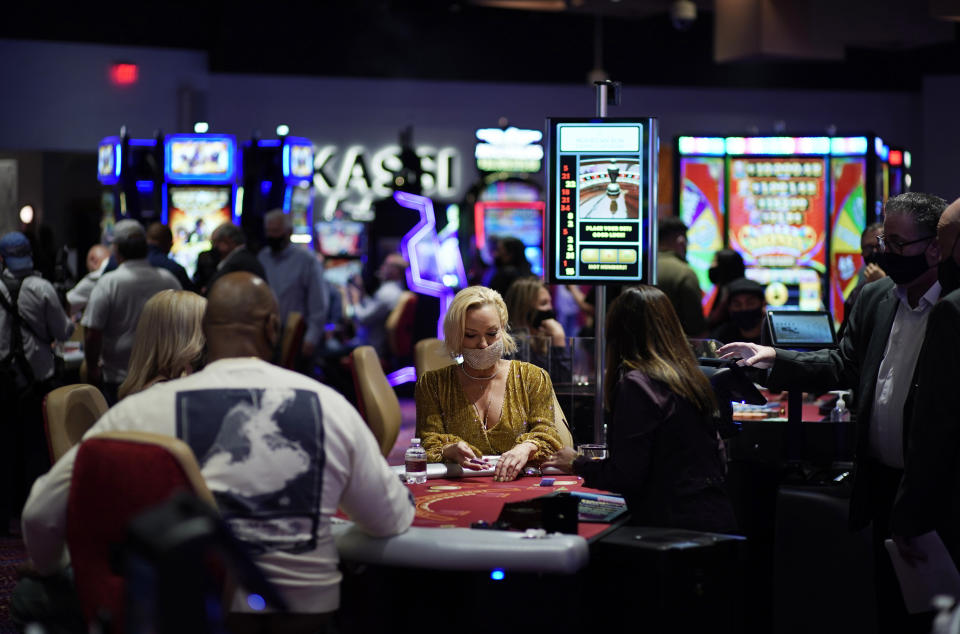 FILE - In this March 25, 2021, photo, people gamble while wearing masks as a precaution against the coronavirus at the opening night of the Mohegan Sun Casino at Virgin Hotels Las Vegas in Las Vegas. Nevada casinos reported near-record March 2022 house winnings, while the airport in Las Vegas reported passenger traffic almost as heavy as pre-pandemic levels and tourism officials marked another big jump in visitor volume. (AP Photo/John Locher, File)