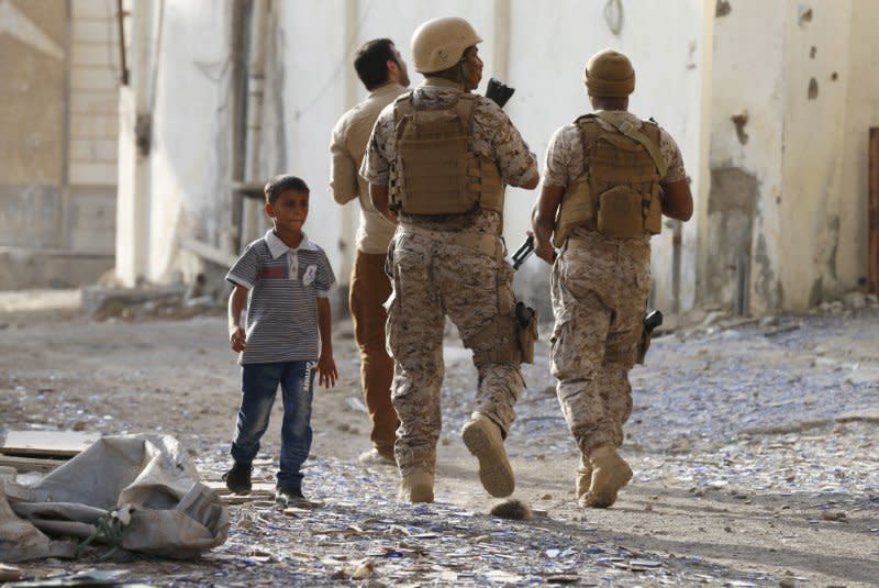 A boy walks past soldiers from the Saudi-led coalition patrolling a street in Yemen's southern port city of Aden September 26, 2015.  REUTERS/Faisal Al Nasser