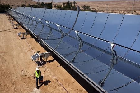 A worker walks next to parabolic mirrors tracking the sun at the research site of solar power company Brenmiller Energy in Israel's Negev desert, near the town of Dimona in this file photo taken on September, 9, 2014. REUTERS/ Nir Elias