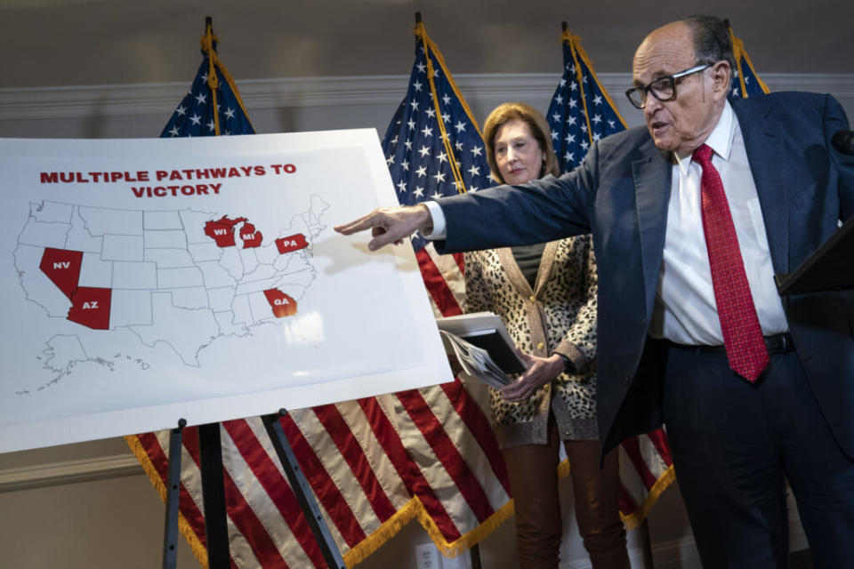 Rudy Giuliani points to a map as he speaks to the press about various lawsuits related to the 2020 election, inside the Republican National Committee headquarters on November 19, 2020 in Washington, DC. Also pictured, at center, is attorney Sidney Powell. (Photo by Drew Angerer/Getty Images)