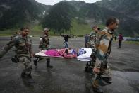 Indian army soldiers carry an injured of a cloudburst for treatment, at Baltal, 105 kilometers (65miles) northeast of Srinagar, Indian controlled Kashmir, Saturday, July 9, 2022. At least eight pilgrims have been killed after a cloudburst triggered a flash flooding during an annual Hindu pilgrimage to an icy Himalayan cave in Indian-controlled Kashmir. Officials say the cloudburst near the hollowed mountain cave revered by Hindus on Friday sent a wall of water down a mountain gorge and swept about two dozen encampments and two makeshift kitchens. (AP Photo/Mukhtar Khan)