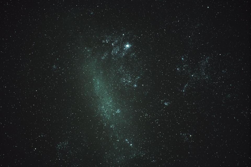 Green gas smears across a backdrop of stars in this close-up photo of the Large Magellanic Cloud.