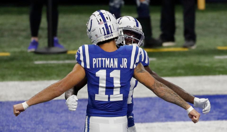 Michael Pittman Jr. (11) and Zach Pascal (14) bump chests before a game against the New England Patriots.