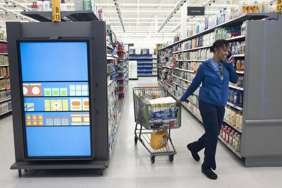 FILE - In this April 24, 2019, file photo customer pulls her shopping cart past an information kiosk at a Walmart Neighborhood Market in Levittown, N.Y. On Wednesday, June 12, the Labor Department reports on U.S. consumer prices for May. (AP Photo/Mark Lennihan, File)