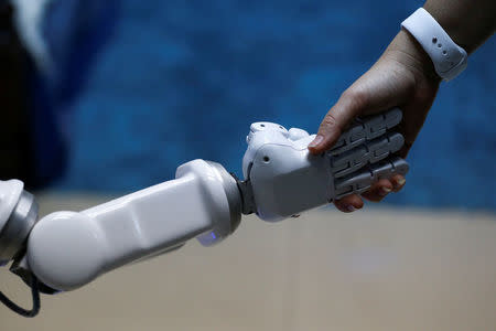 Chalermpon Punnotok, CEO of CT Asia Robotics gives a hand to a robot during an interview with Reuters in Bangkok, Thailand July 5, 2016. REUTERS/Athit Perawongmetha