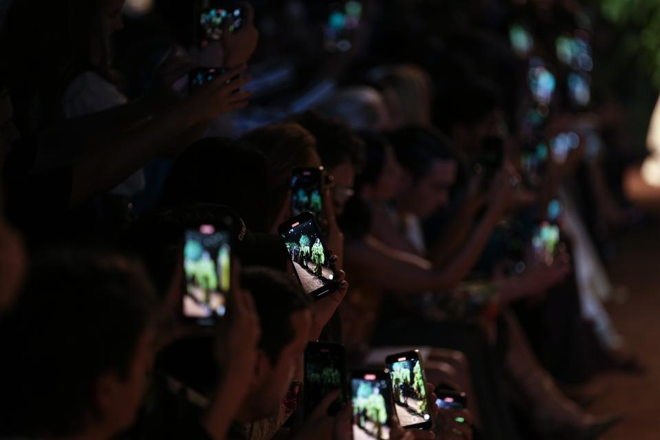 Guests use their cell phones to record the Roberto Cavalli women's Spring Summer 2024 collection presented in Milan, Italy, Wednesday, Sept. 20, 2023. (AP Photo/Luca Bruno)
