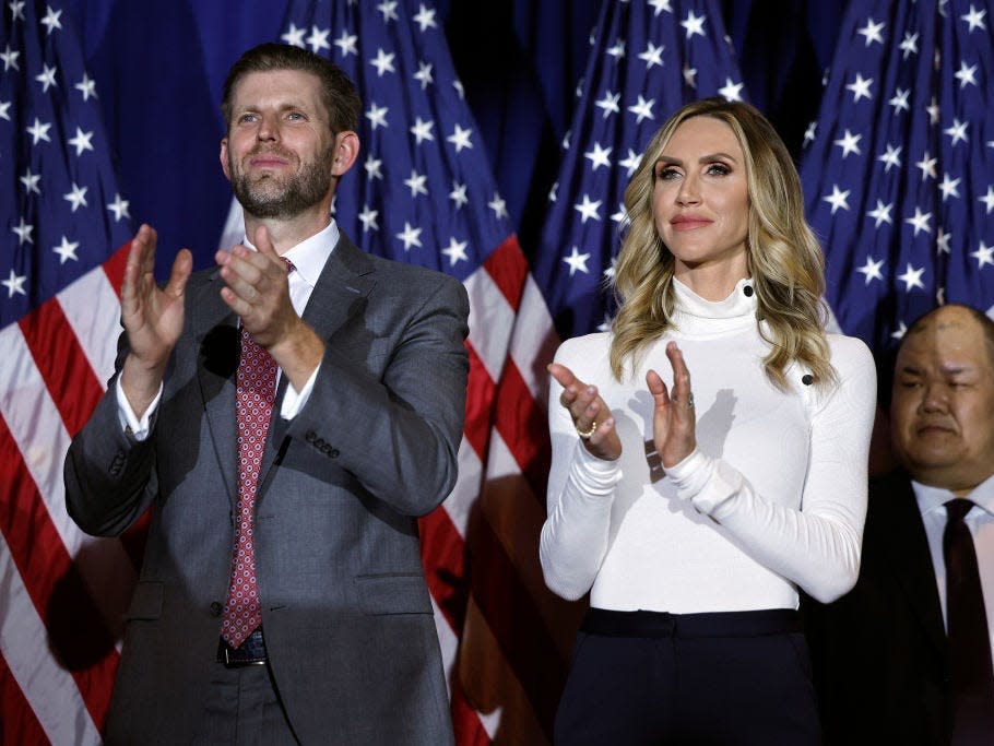 Eric Trump and Lara Trump applaud in front of American flags