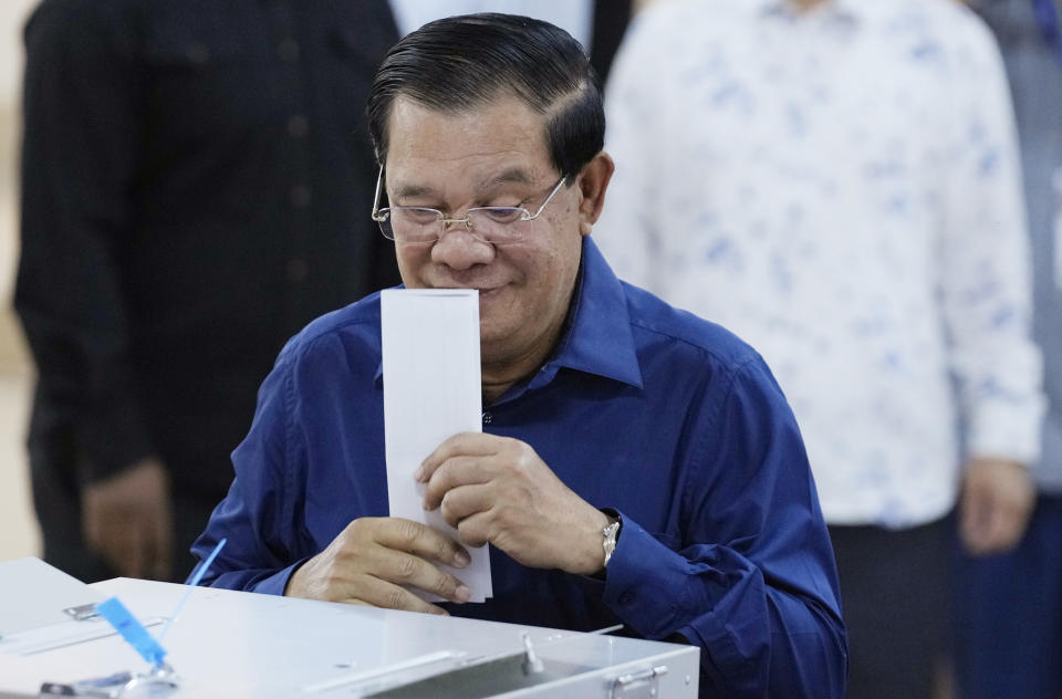 Cambodian Prime Minister Hun Sen of the Cambodian People's Party (CPP) kisses a ballot before voting at a polling station at Takhmua in Kandal province, southeast Phnom Penh, Cambodia, Sunday, July 23, 2023. Cambodians go to the polls Sunday with incumbent Prime Minister Hun Sen and his party all but assured a landslide victory thanks to the effective suppression and intimidation of any real opposition that critics say has made a farce of democracy in the Southeast Asian nation. (AP Photo/Heng Sinith)