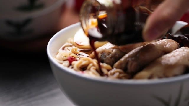 Pouring chicken essence to bowl of instant noodles