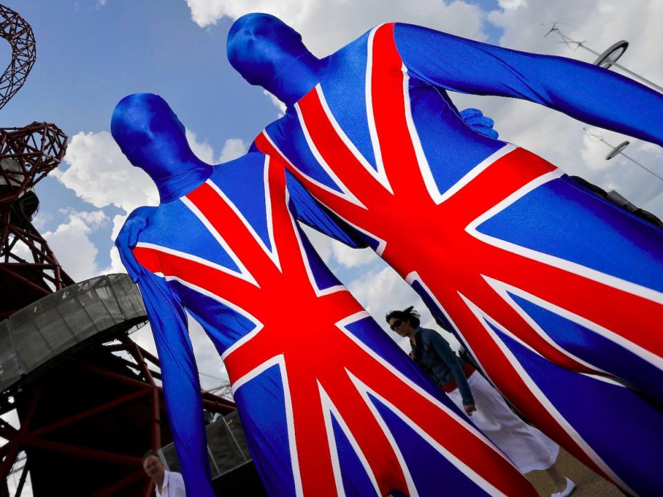 In this Thursday, Aug. 2, 2012 photo, British fans wearing leotards in the colors of the flag pose for other spectators to take pictures of them in front of the Orbit Tower in Olympic Park at the 2012 Summer Olympics, in London. Patriotism and the games have always gone together, but gone are the days when one just waved a flag. Now flags are worn, seen all over London and especially at Olympic Park and other spots where the games are being played. ()