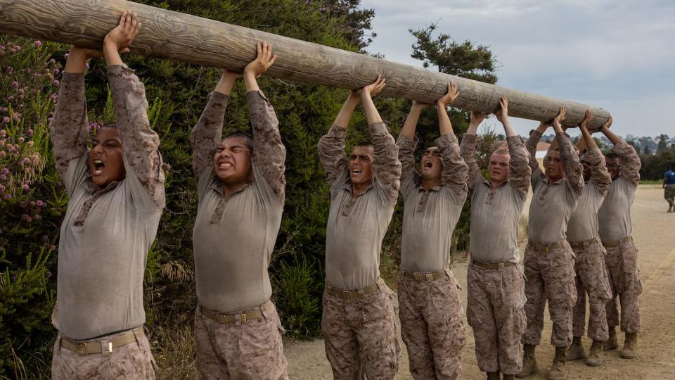 Recruits in San Diego carry a 250-pound log on July 31, while clad in desert-colored flame-resistant organizational gear. (Lance Cpl. Jacob B. Hutchinson/Marine Corps)