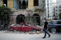 A man walks past a destroyed car at a neighborhood near the scene of Tuesday's explosion that hit the seaport of Beirut, Lebanon, Friday, Aug. 7, 2020. Rescue teams were still searching the rubble of Beirut's port for bodies on Friday, nearly three days after a massive explosion sent a wave of destruction through Lebanon's capital. (AP Photo/Thibault Camus)