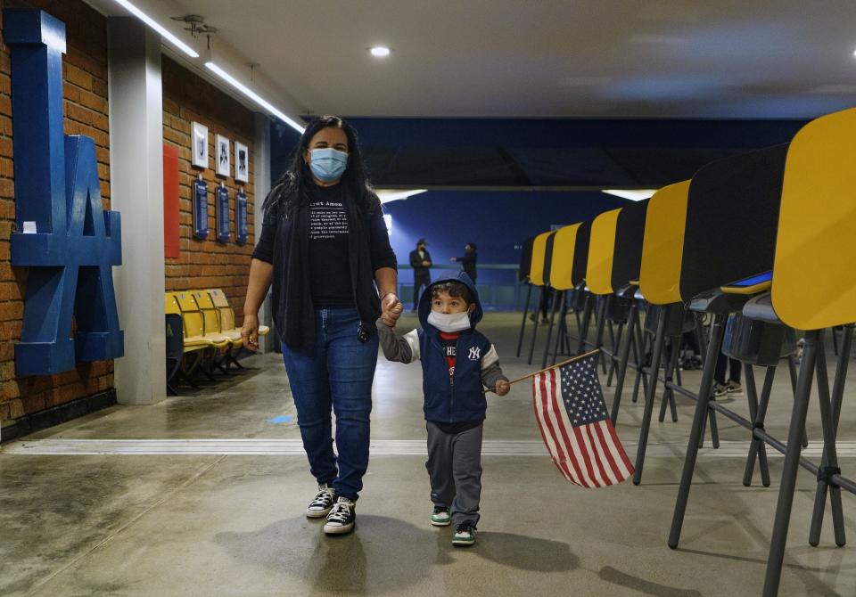 FILE - In this Nov. 2, 2020, file photo, Lisa Carrera, a former Los Angeles Unified School history teacher from La Puente, Calif., holds the hand of her grandson Maverick, 2, after casting her ballot in-person at the Top of the Park at Dodger Stadium in Los Angeles. Democrats plan to move quickly on one of the first bills of the new Congress, which would set federal election standards. The For the People Act would require states to offer early voting, same-day registration and the option of absentee voting for all registered voters. (AP Photo/Damian Dovarganes, File)