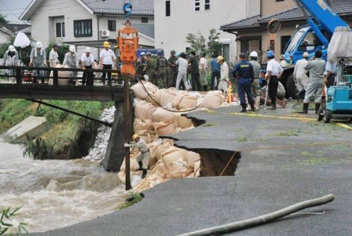 Japanese soldiers and other workers repair a collapsed bank of the Koura River in Kurume, Fukuoka Prefecture, on July 14. Flood victims in Japan have begun a full-scale clean-up operation after record rainfall forced hundreds of thousands to flee and left at least 32 dead or missing