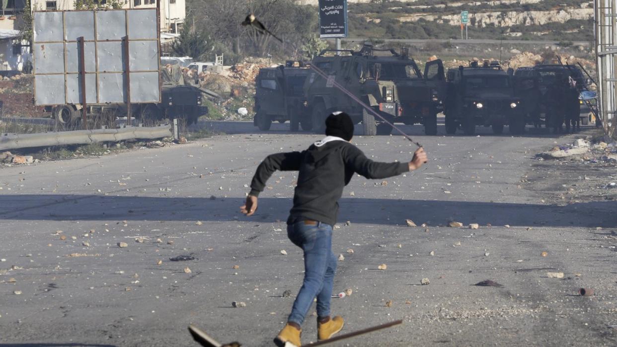 Ein Palästinenser wirft Steine auf israelische Sicherheitskräfte. Die israelische Armee hat die Stadt Ramallah, das Verwaltungszentrum der Palästinenser im Westjordanland, abgeriegelt. Foto: Mahmoud Illean/AP