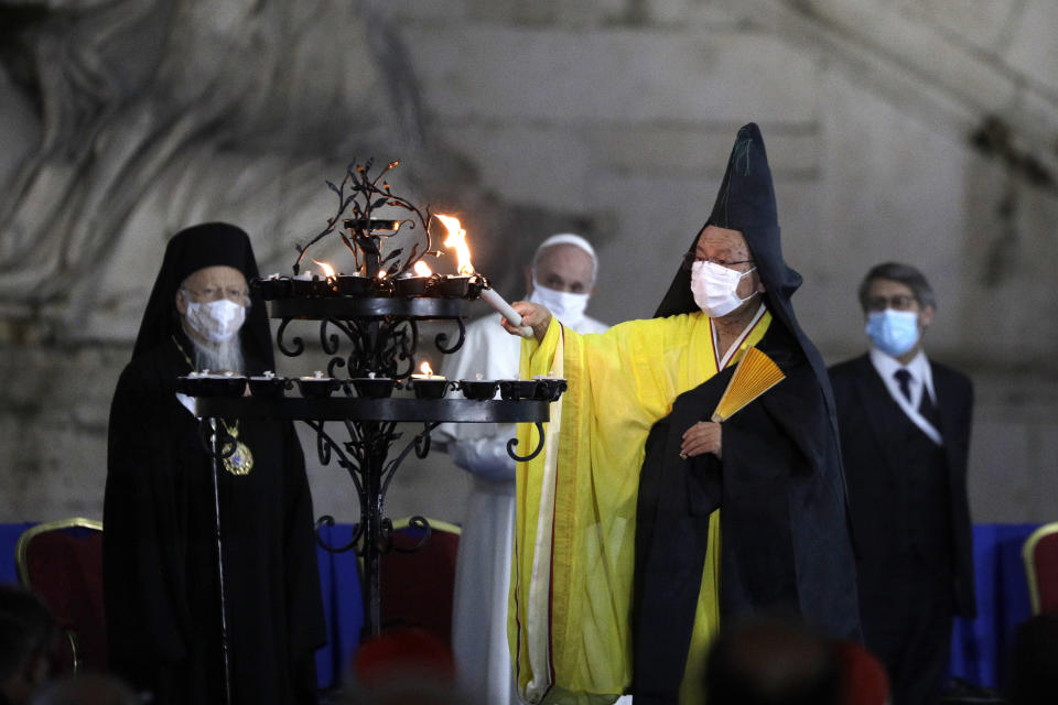 Buddhist monk Shoten Minegishi lights a candle for peace as Bartolomew I, Patriarch of Constantinopolis, Pope Francis and Haim Korsia, Chief Rabbi of France, look on, during an inter-religious ceremony for peace in the square outside Rome's City Hall, Tuesday, Oct. 20, 2020 (AP Photo/Gregorio Borgia)