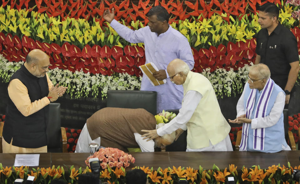 Indian Prime Minister Narendra Modi, center, touches the feet of senior most Bharatiya Janata Party (BJP) leader L.K.Advani after being elected ruling alliance leader, in New Delhi, India, Saturday, May 25, 2019. BJP president Amit Shah announced Modi's name as the leader of the National Democratic Alliance in a meeting of the lawmakers in the Central Hall of Parliament in New Delhi, paving the way for Modi's second five-year term as prime minister after a thunderous victory in national elections. (AP Photo/Manish Swarup)