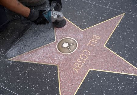 A worker cleans graffiti on actor Bill Cosby's star on the Hollywood Walk of Fame in Los Angeles December 5, 2014. REUTERS/Phil McCarten