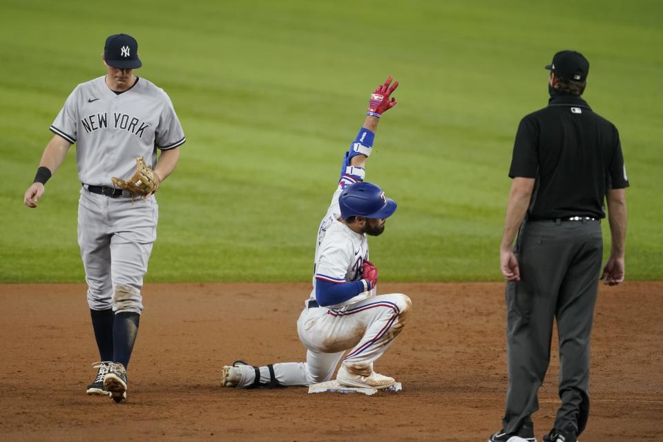 New York Yankees second baseman DJ LeMahieu, left, walks past and umpire Ryan Additon, right, looks on as Texas Rangers' Isiah Kiner-Falefa, center, celebrates his run-scoring double in the second inning of a baseball game in Arlington, Texas, Monday, May 17, 2021. Rangers' David Dahl scored on the hit. (AP Photo/Tony Gutierrez)