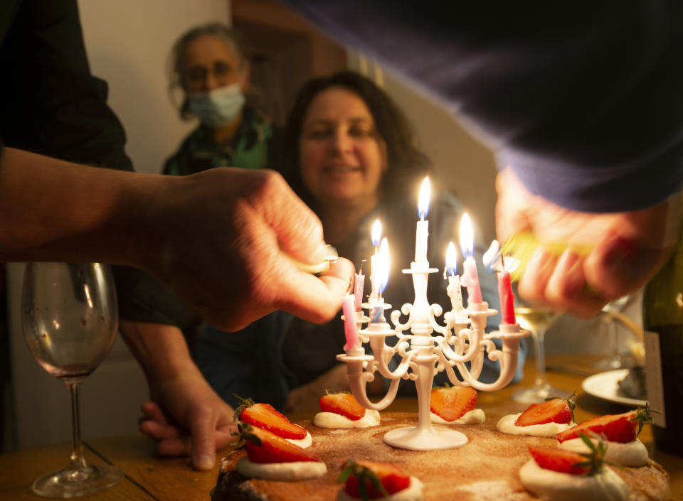 Nathalie Sartor, center, smiles as candles are lit to celebrate her 57th birthday in the apartment that she and her family share in Montmartre, Paris, on May 14, 2021. France began easing out of lockdown in mid-May, as vaccinations started to make headway against the country's coronavirus epidemic that has claimed more 110,000 lives. With shops, museums, cafes and restaurants open again, Nathalie is looking forward to taking a road trip through France in the coming summer months.(AP Photo/Joao Luiz Bulcao)