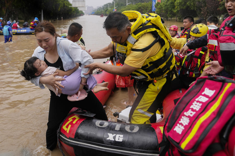 A rescuer helps a woman with a child disembark from a rubber boat as trapped residents evacuate through floodwaters in Zhuozhou in northern China's Hebei province, south of Beijing, Wednesday, Aug. 2, 2023. China's capital has recorded its heaviest rainfall in at least 140 years over the past few days. Among the hardest hit areas is Zhuozhou, a small city that borders Beijing's southwest. (AP Photo/Andy Wong)