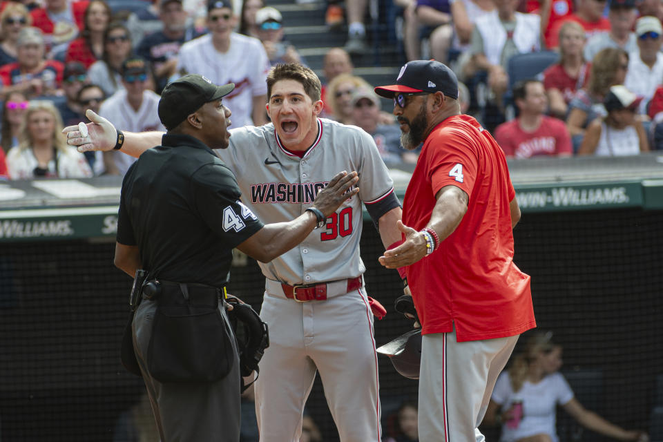 Washington Nationals' Jacob Young (30) argues a called third strike with umpire Malachi Moore, left, as Nationals manager Dave Martinez, right, joins in during the third inning of a baseball game against the Cleveland Guardians in Cleveland, Saturday, June 1, 2024. (AP Photo/Phil Long)