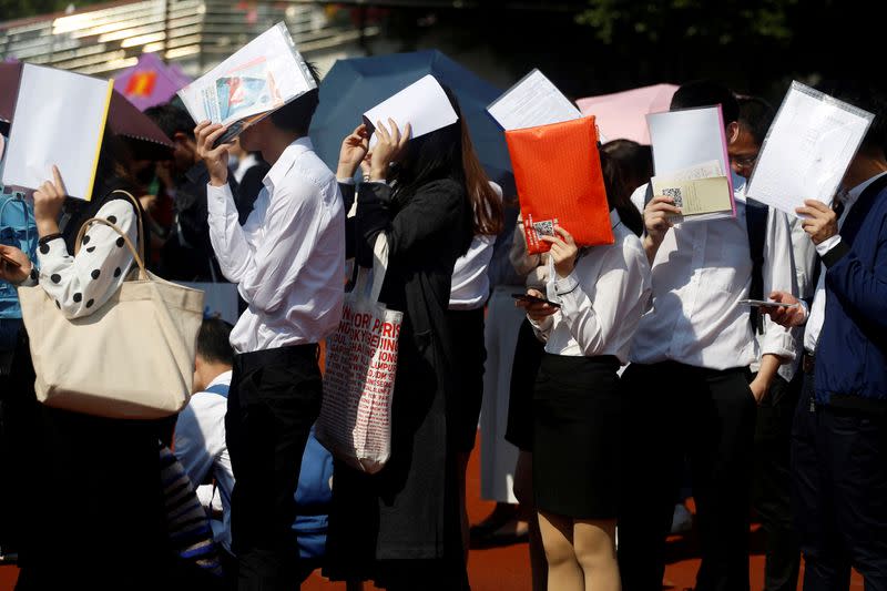 FILE PHOTO: Students shield themselves from the sun as they line up at a job fair at a university in Guangzhou