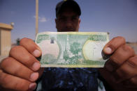 <p>An Iraqi policeman displays a 10,000-Iraqi dinar banknote bearing an image of Mosul’s iconic leaning minaret, known as the “Hadba” (Hunchback), on June 22, 2017, in Mosul. (Photo: Ahmad al-Rubaye/AFP/Getty Images) </p>