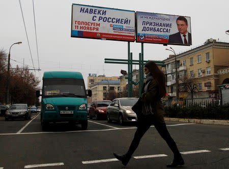 FILE PHOTO: A woman crosses a street past the campaign board of Leonid Pasechnik, acting head of the self-proclaimed separatist Luhansk People's Republic (LNR), ahead of the upcoming vote for a new leader in Luhansk, Ukraine November 9, 2018. REUTERS/Alexander Ermochenko