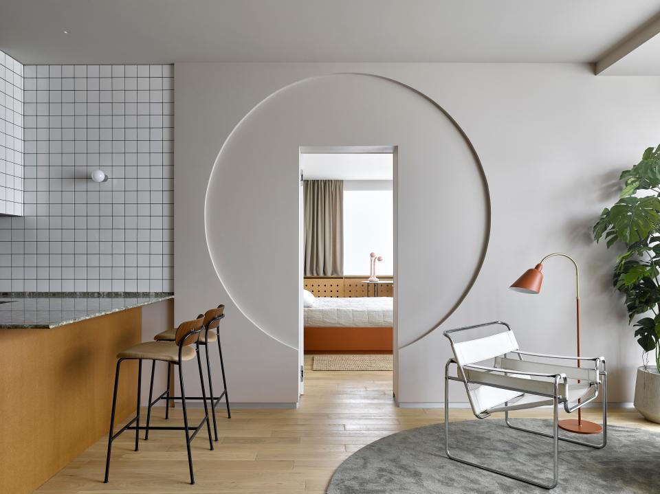 A circular door frame softly separates the living area from the main bedroom.