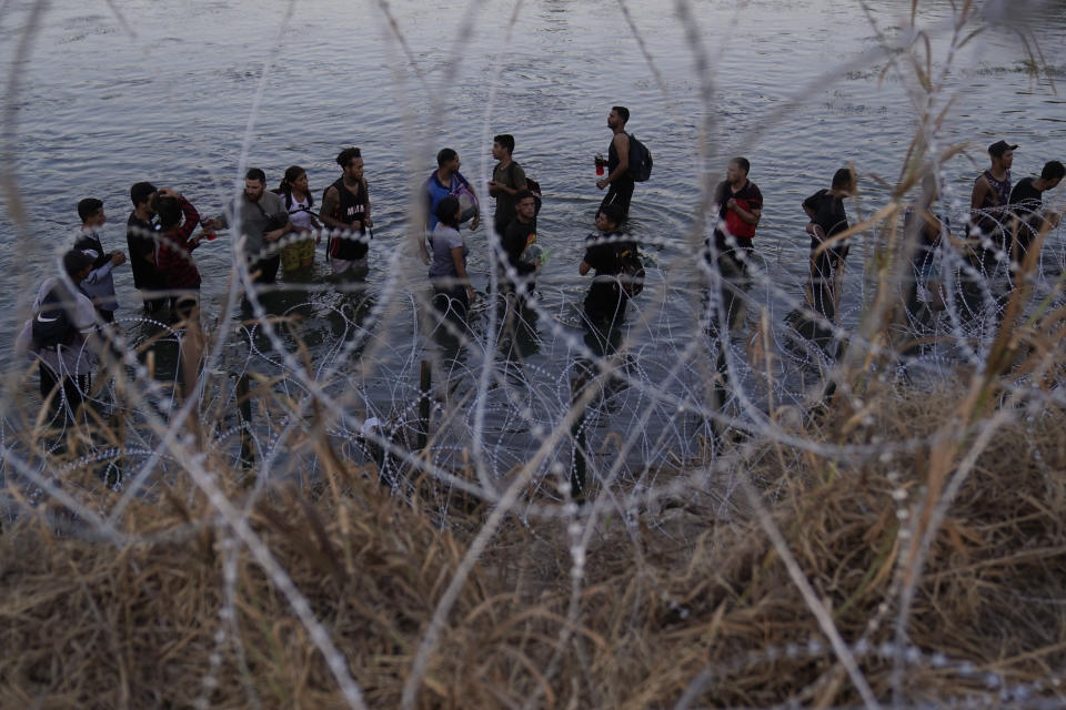 Migrants wait to climb over concertina wire after they crossed the Rio Grande and entered the U.S. from Mexico, Saturday, Sept. 23, 2023, in Eagle Pass, Texas. (AP Photo/Eric Gay)