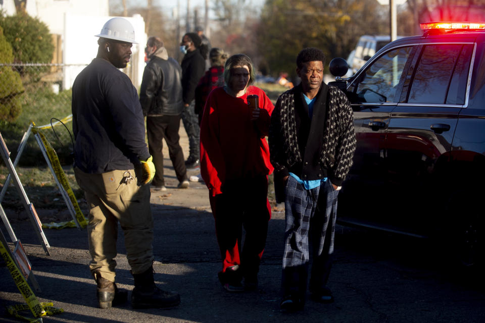 Neighbors and residents of Hogarth Avenue watch on as police, fire and other emergency personnel work at the scene Tuesday, Nov. 23, 2021 after a house fire and explosion in Flint, Mich. (Jake May/The Flint Journal via AP)