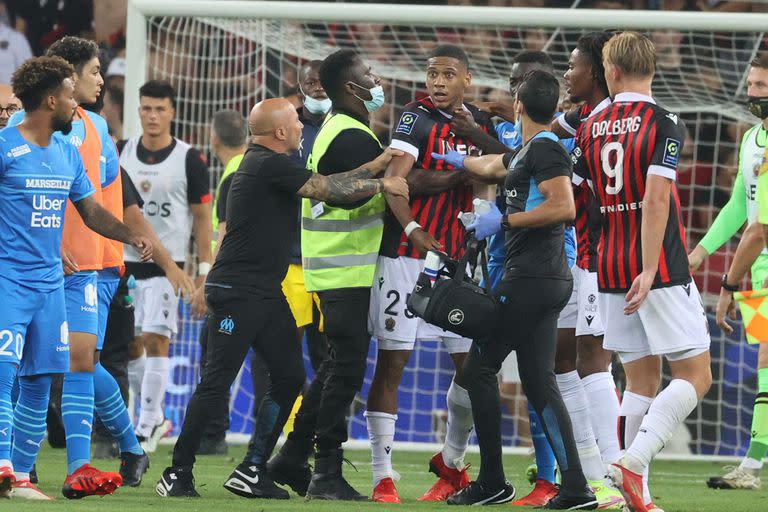 El entrenador argentino del Marsella Jorge Sampaoli (CR) frena al defensor francés de Niza Jean-Clair Todibo mientras los fanáticos intentan invadir el campo durante el partido de fútbol francés L1 entre OGC Nice y Olympique de Marseille (OM) en el estadio Allianz Riviera en Niza, en el sur Francia el 22 de agosto de 2021.