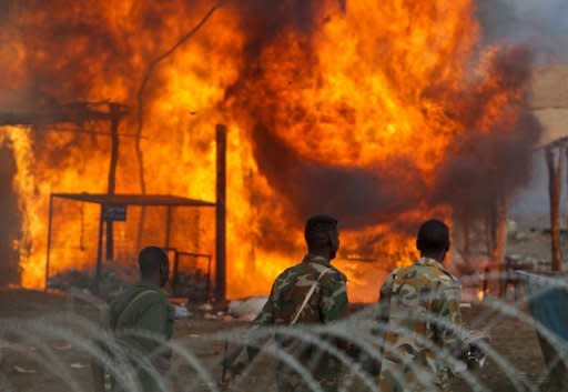 Armed uniformed men walking past burning businesses and homesteads locally known as 'tukuls' in the centre of the disputed Sudanese central town of Abyei. Fresh satellite images of Sudanâs flashpoint Abyei area provide evidence of war crimes committed by the northern army, including "state-sponsored ethnic cleansing," monitors alleged