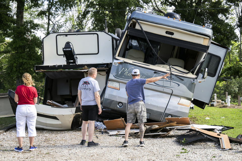 People survey damage near an overturned camper trailer resting against an RV Tuesday, May 14, 2024, following severe weather on Monday night on Paul Road in Cecilia, La. (Leslie Westbrook/The Times-Picayune/The New Orleans Advocate via AP)