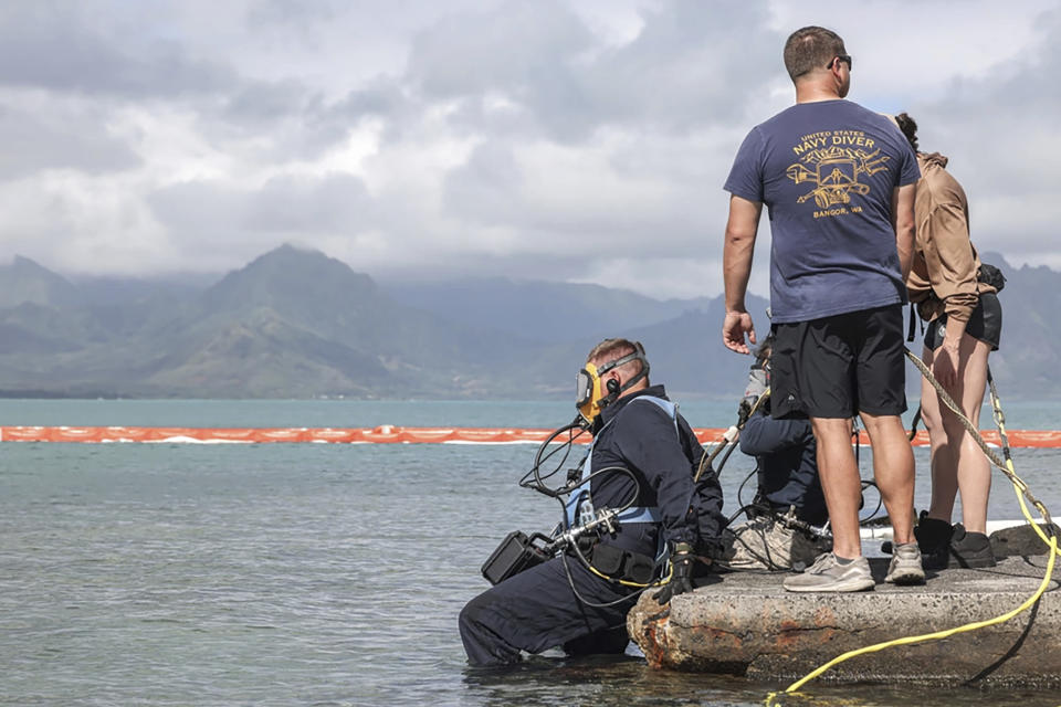 This photo provided by U.S. Marine Corps, U.S. Navy Sailors with Company 1-3, Mobile Diving and Salvage Unit 1, enter the water to retrieve the aircraft flight recorder from a downed U.S. Navy P-8A Poseidon in waters just off the runway at Marine Corps Air Station Kaneohe Bay, Marine Corps Base Hawaii, Thursday, Nov. 23, 2023. The flight data recorder has been recovered as the military continues to plan for the aircraft’s removal.(Lance Cpl. Hunter Jones/U.S. Marine Corps via AP)