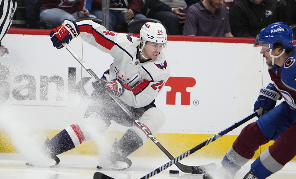 Washington Capitals center Connor McMichael, left, collects the puck as Colorado Avalanche defenseman Samuel Girard pursues in the second period of an NHL hockey game Wednesday, Jan. 24, 2024, in Denver. (AP Photo/David Zalubowski)