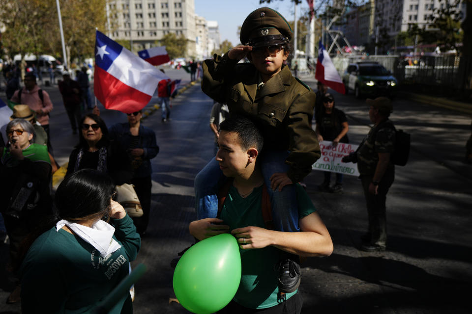 A father carries his daughter dressed as a Chilean police on his shoulders to a demonstration seeking justice for police officers killed in the line of duty, in Santiago, Chile, Saturday, April 27, 2024. Three police officers were killed early Saturday, in Cañete, Chile's Bío Bío region. (AP Photo/Esteban Felix)